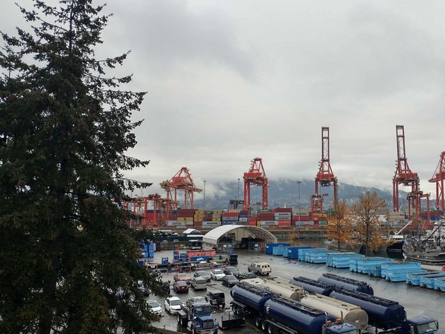 A shipping yard with cranes, cars and containers.