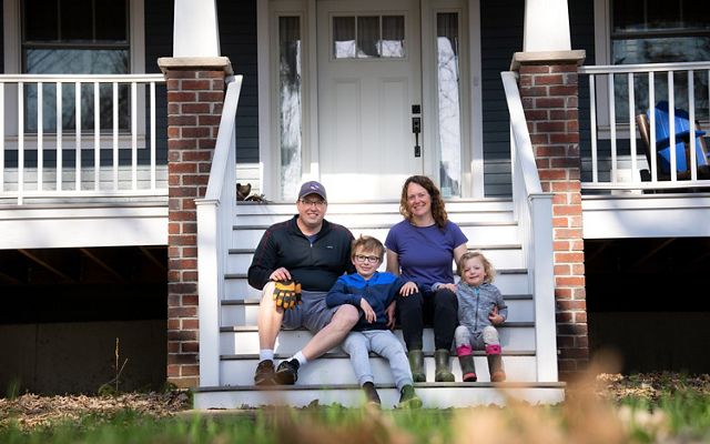 Scott and Leslie Svacina sit with their two children on the front steps of their house.