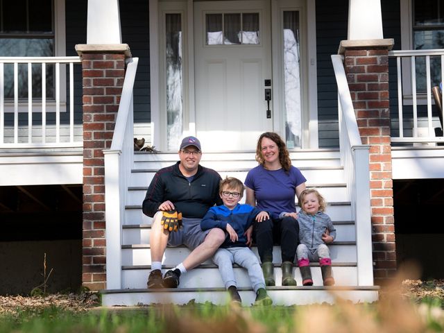 Scott and Leslie Svacina sit with their two children on the front steps of their house.