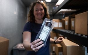 Leslie Svacina holds up to the camera a vacuum-sealed goat sausage.