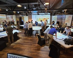 Several people gather around tables to look for information.