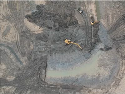 An aerial view of construction vehicles working in a very muddy area.