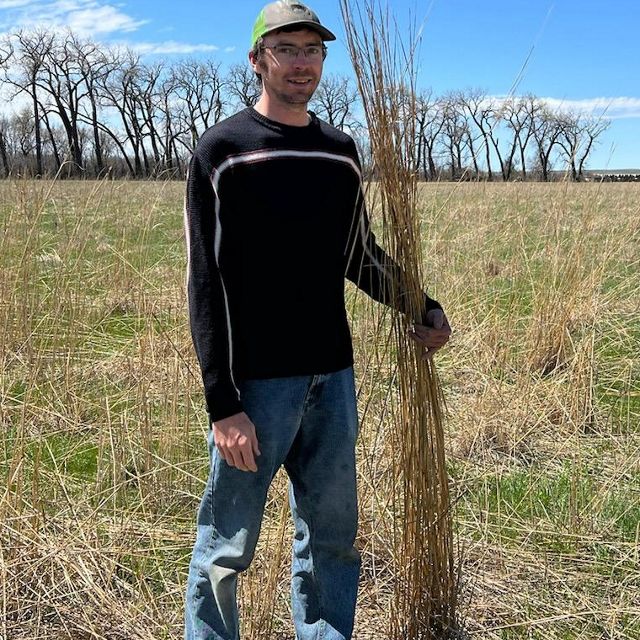 Pete Kronberg holds up blades of grass that reach to his head.