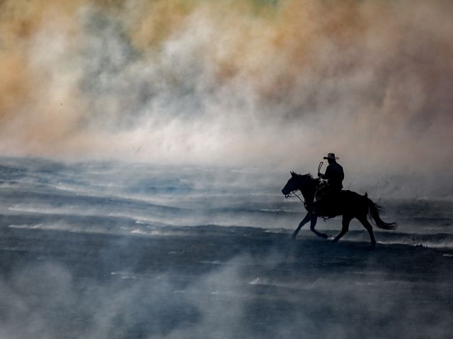 A person on horseback riding through smoke.