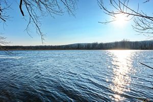 The sun sets over a large pond.