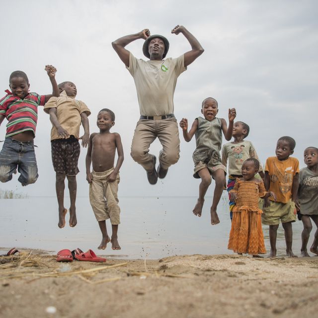 a man and a group of children jumping off the ground