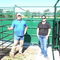 man and women standing in front of metal corral.