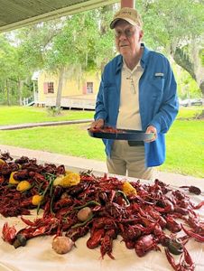 A man wearing a hat stands in front of a crab boil.