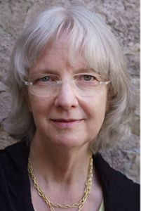 A woman wearing glasses smiles at the camera.