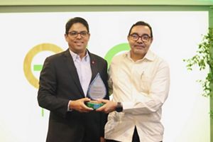 Two men stand with an award on a stage. 