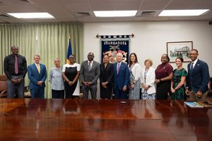 A group of Board members and Government officials stand at a table in Barbados.
