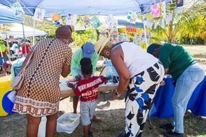 A family stands at a booth at the coral festival and makes art.