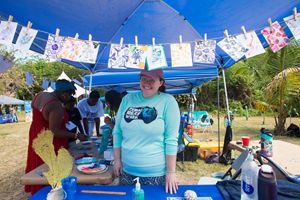 A woman stands smiling at a booth at the Inaugural Coral Conservation Festival in the Virgin Islands.