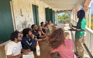 Learning exchange participants sit at a table in a breezeway as they learn more about coral fertilization.