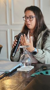 A woman speaks at a microphone. 