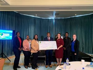 Grant recipients stand with a physically large check at the grant awarding ceremony. 