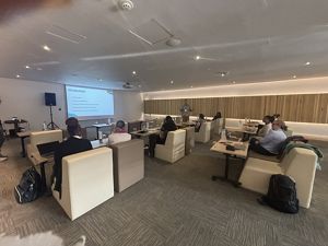 People sit at chairs while a presentation is on an overhead projector. 