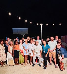 A group of smiling event participants pose for a photo on an evening in the Dominican Republic. 