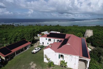 An aerial view of solar panels on the roof of the building and the historic windmill.
