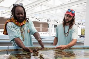 Two men stand next to a coral spawning tank at TNC's Coral Innovation Hub. 