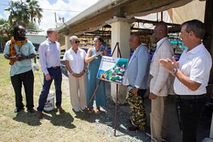 A group of people stand alongside a sign to commemorate the Unplugging Ceremony to transition to renewable energy. 