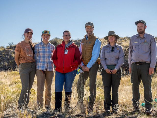 Six people stand together outside and pose for the camera.