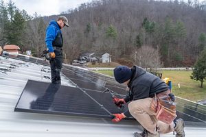 Two workers stand on a roof as they complete a solar panel installation in Kentucky.