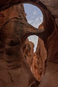 A blue sky if visible through a red rock canyon in a desert landscape. 