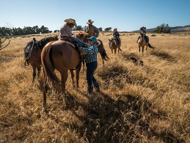 A ranch family rides horses in a grassy area