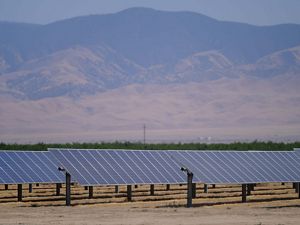 A solar array in the foreground with mountains in the background.
