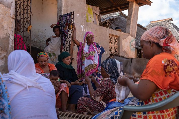 Women from the Mtangawanda Women's Association chat and do embroidery.