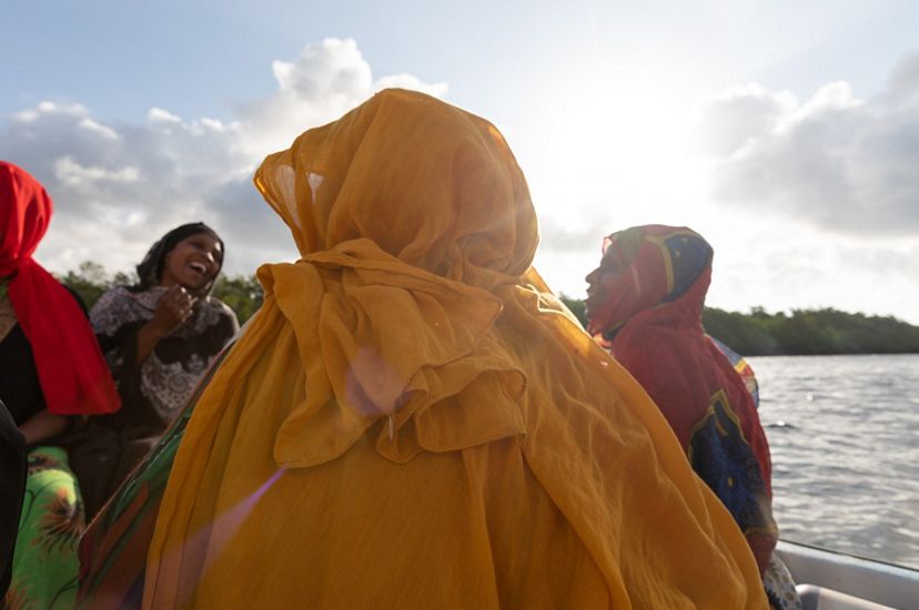 Women in colorful scarves ride in a boat.