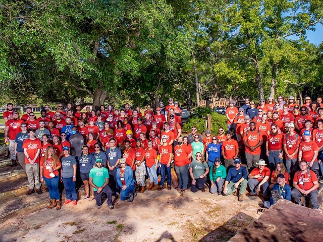 Nearly 100 GulfCorps members stand in red shirts for a group photo.
