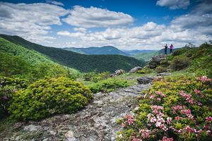 A mountain view with two people on the top of a rock.