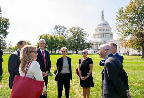 Several people stand outside of a state capitol building.