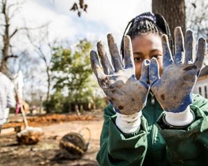 Student shows dirty gloves (foreground)