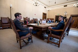 Several people sit around a conference table in a room at the Washington state house.