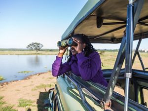 A visitor looking through binoculars for wildlife in Nairobi National Park in Kenya.