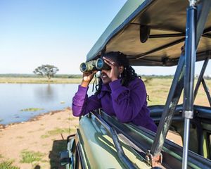 A visitor looking through binoculars for wildlife in Nairobi National Park in Kenya.