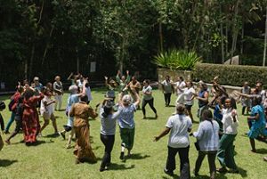 A group of people participate in an outdoor activity and run across grass.