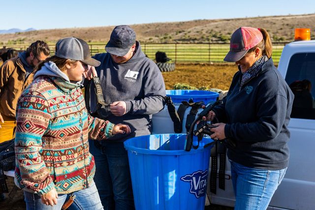 A small group of people stand together working around blue plastic barrels.