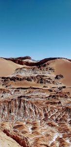 Paisaje de dunas de arena del desierto con lo que parece ser una cascada de arena que baja por el centro de las dunas; el "agua" es en realidad sal.