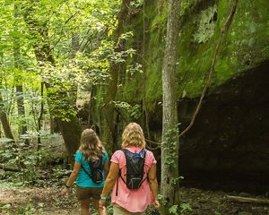 Two hikers walk past Mantle Rock.