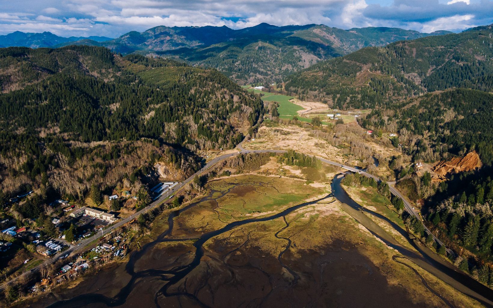 Aerial view of Miami Wetlands Preserve in Oregon on a sunny day with puffy clouds over mountains in the background.
