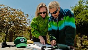 Two people stand outside and look at a map on a table.