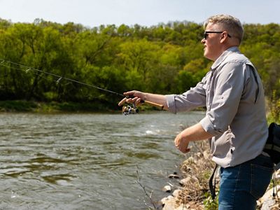 A man casting a fishing line into a river.