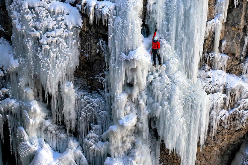 Senderista escalando una cascada congelada.