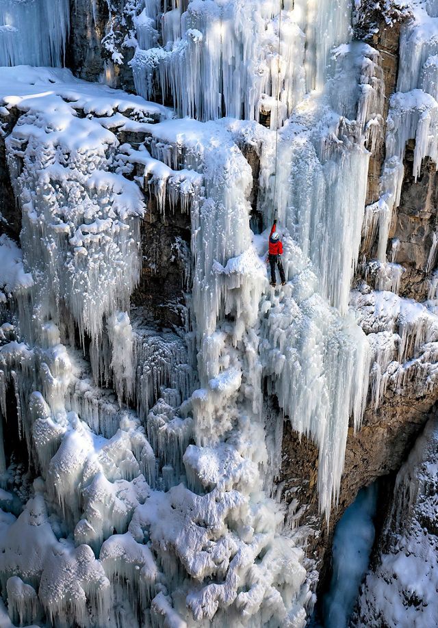 Senderista escalando una cascada congelada.