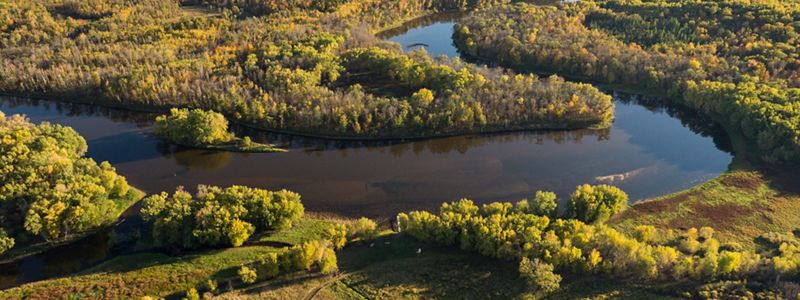 A river slowly winds through a landscape of forest and fields.