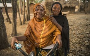 Two women stand next to bike